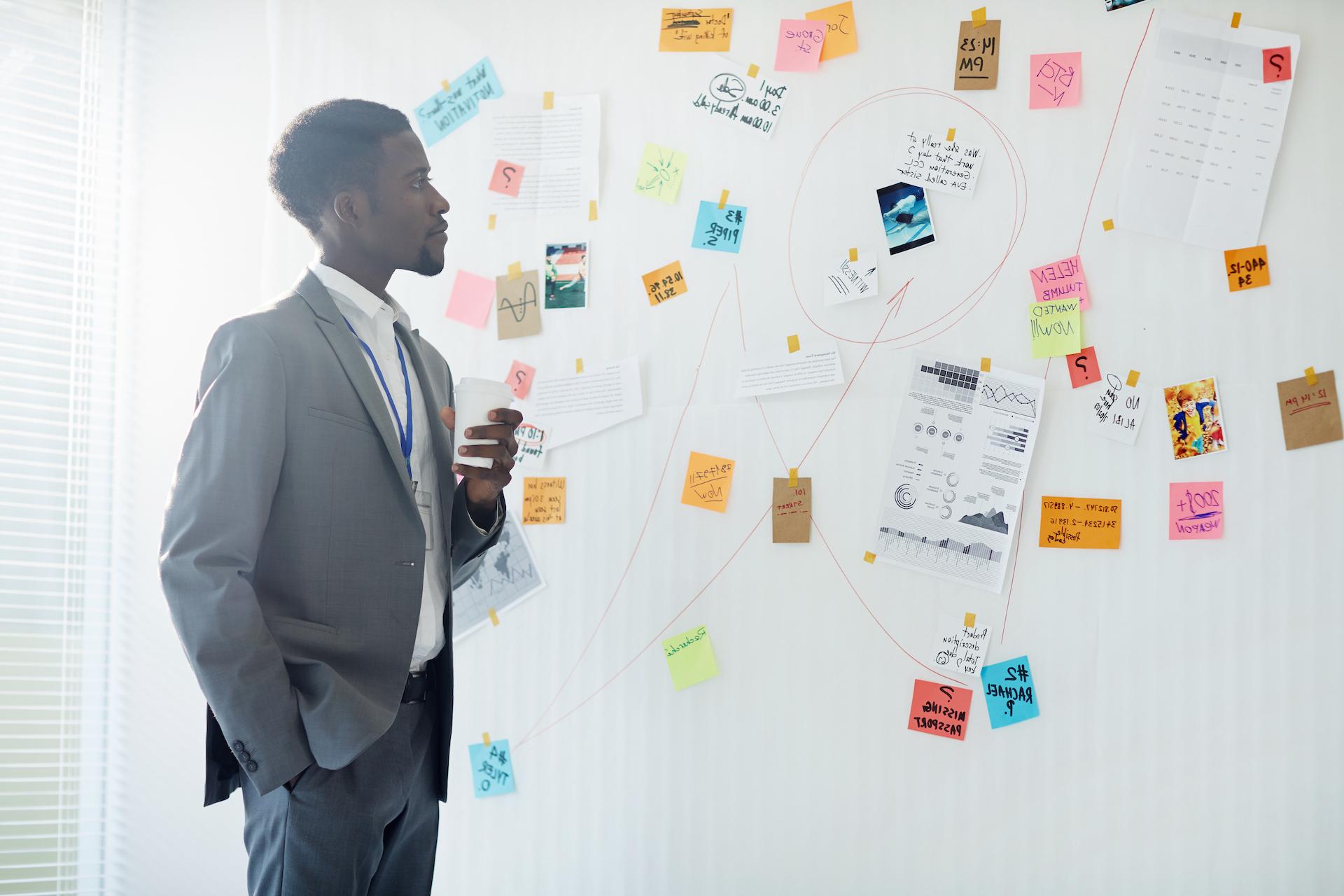 man looking at post-it notes on wall