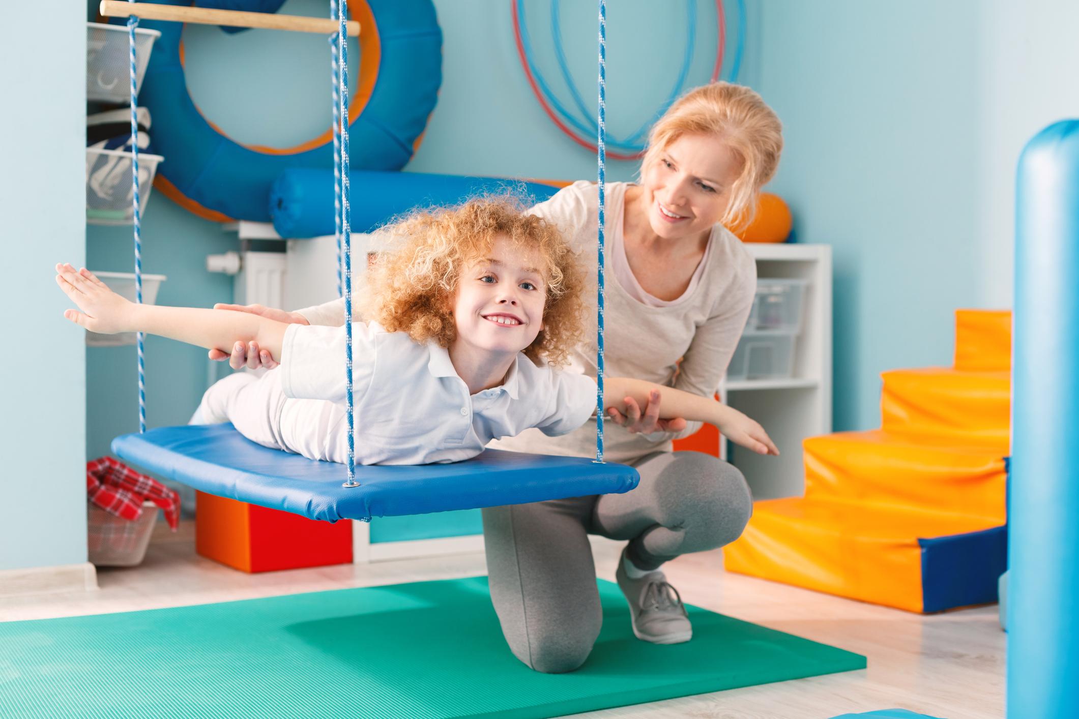 therapist helping child on swing